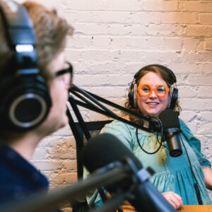 Man interviewing a woman in the studio with headphones and large microphones