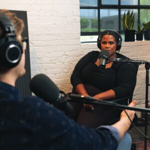 Man interviewing a woman in the studio with headphones and large microphones