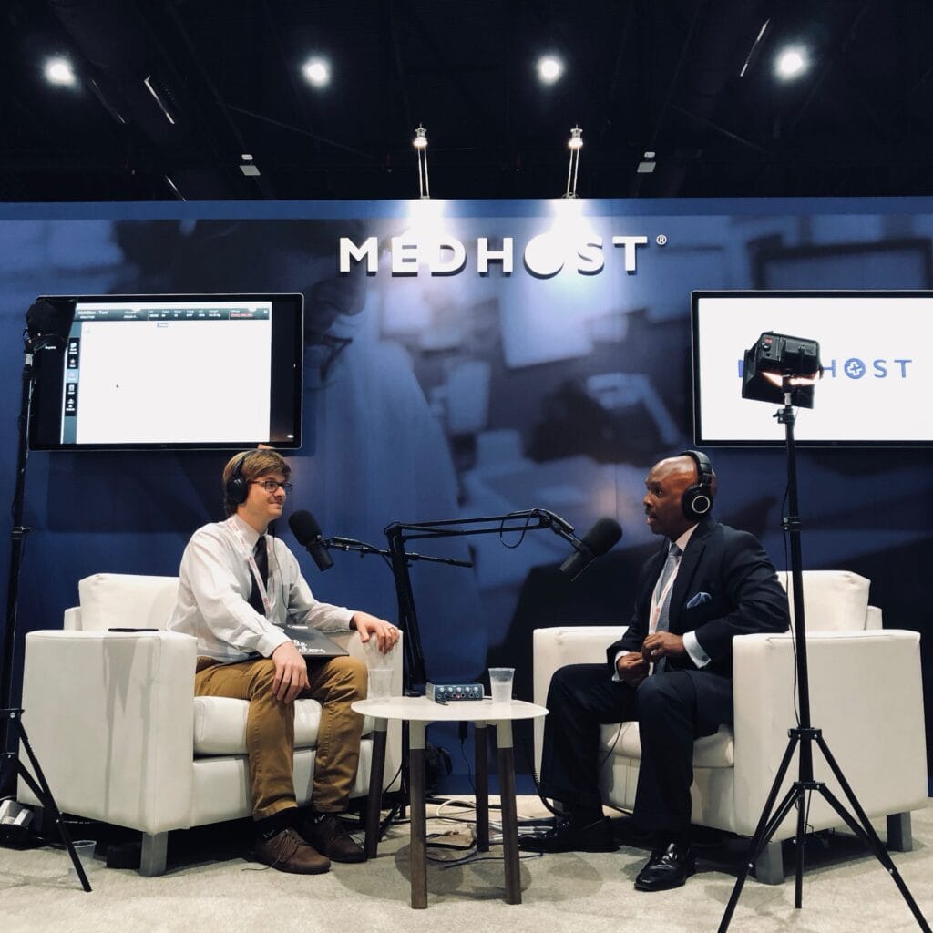 Interview in the trade show booth with studio lights, headphones, and large microphones